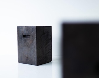 May include: A dark wood stool with a rectangular shape and a cut-out handle on the front.