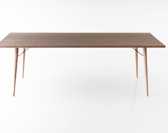 Puede incluir: Una mesa rectangular de madera con un acabado marrón claro y cuatro patas delgadas. La mesa tiene un diseño simple y moderno.