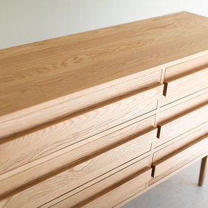 May include: A light wood dresser with six drawers and a simple design. The dresser has a natural wood finish and is made of solid wood.