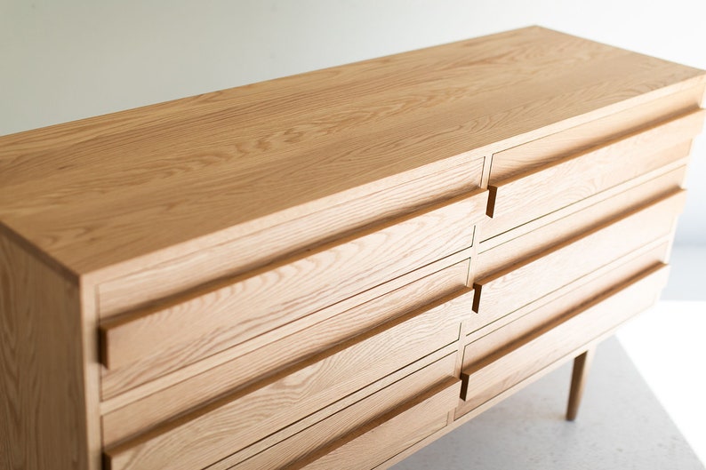 May include: A light wood dresser with six drawers and a simple design. The dresser has a natural wood finish and is made of solid wood.