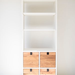 May include: White bookshelf with four wooden drawers. The drawers have black metal handles and are made of reclaimed wood.