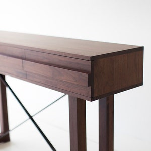 May include: A dark brown wooden console table with two drawers and a black metal X-shaped base.