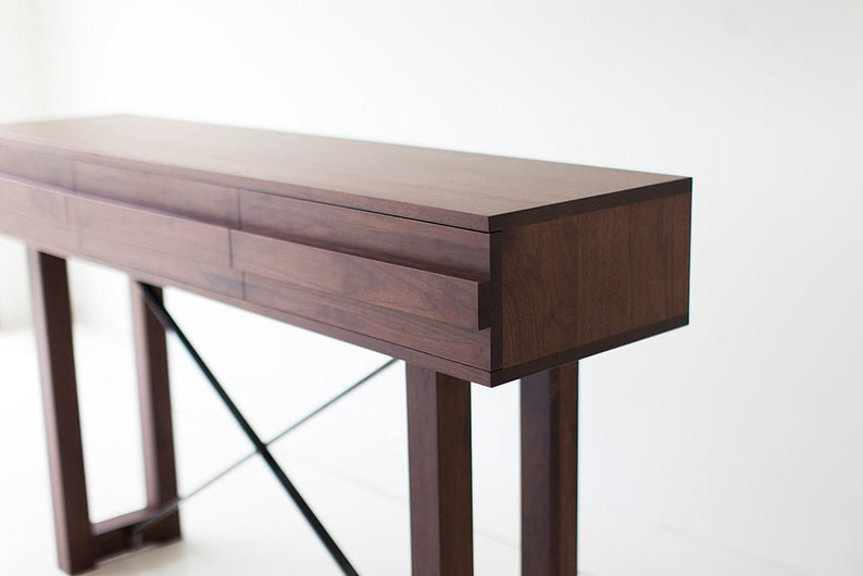 May include: A dark brown wooden console table with two drawers and a black metal X-shaped base.