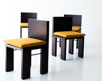 May include: Four dark brown wooden chairs with yellow fabric cushions. The chairs have a simple, modern design with a square back and four legs.