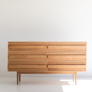 May include: A light wood dresser with six drawers and four legs. The dresser is made of solid wood and has a simple, modern design.
