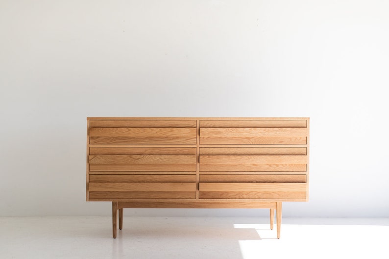 May include: A light wood dresser with six drawers and four legs. The dresser is made of solid wood and has a simple, modern design.