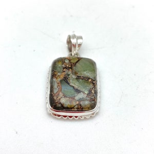 May include: A silver pendant with a rectangular green and brown stone set in a silver frame.