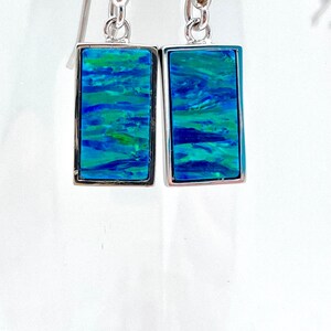 Puede incluir: Un par de pendientes de plata con piedras rectangulares de ópalo azul y verde.