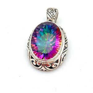 May include: A silver pendant with an oval-shaped iridescent gemstone. The pendant has a detailed filigree design around the gemstone.