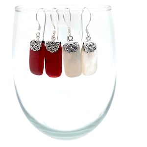 May include: Three pairs of dangle earrings with silver filigree tops and rectangular stones. One pair has red stones, one pair has white stones, and one pair has a combination of red and white stones.