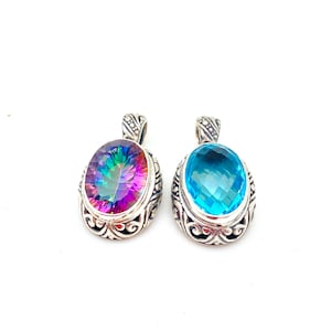 May include: Two silver pendants with oval-shaped gemstones. The pendant on the left has a rainbow-colored gemstone, while the pendant on the right has a light blue gemstone.