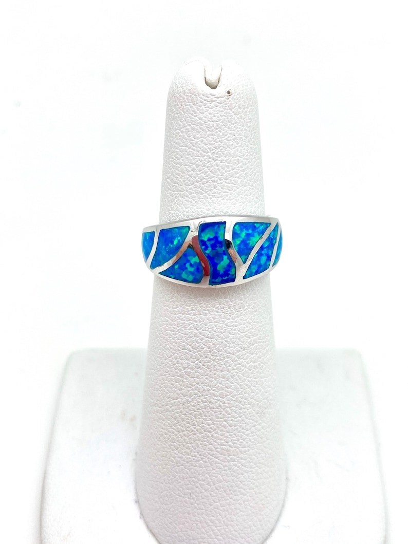 May include: A silver ring with a blue opal inlay. The opal is set in a silver band and has a swirling pattern.