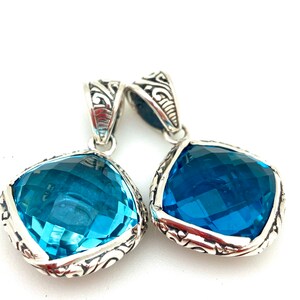 May include: Two silver pendants with blue gemstone accents. The pendants feature intricate silver designs and are perfect for adding a touch of elegance to any outfit.