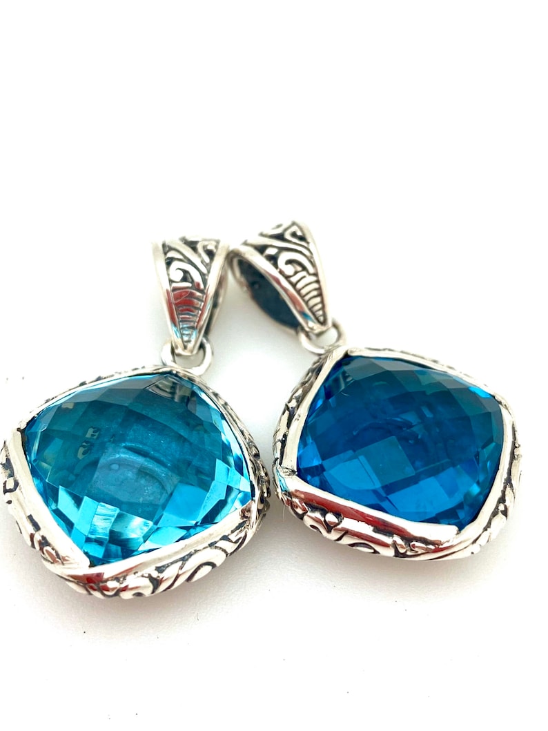 May include: Two silver pendants with blue gemstone accents. The pendants feature intricate silver designs and are perfect for adding a touch of elegance to any outfit.