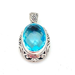 May include: A silver pendant with a large, oval-shaped, light blue gemstone set in a detailed silver frame.