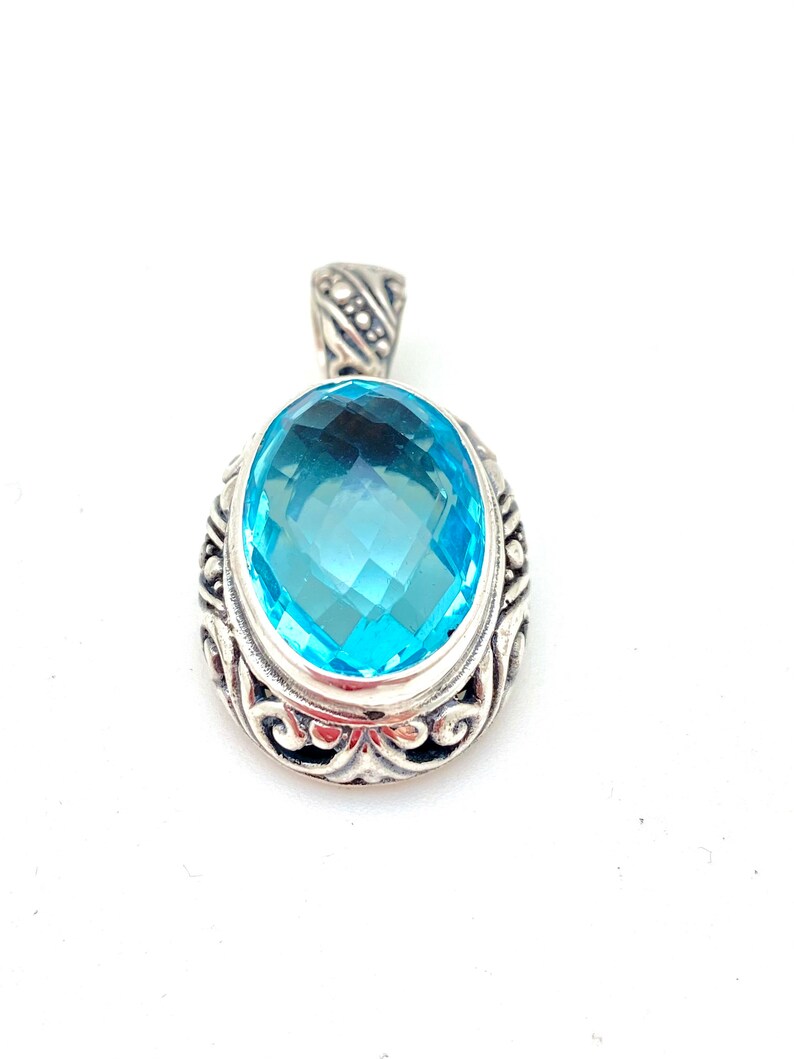 May include: A silver pendant with a large, oval-shaped, light blue gemstone set in a detailed silver frame.