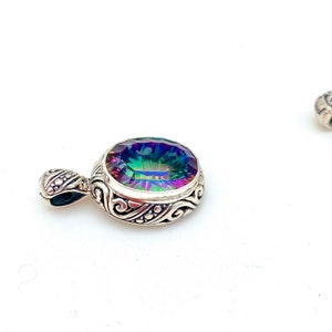 May include: A silver pendant with an iridescent gemstone set in a detailed filigree design.