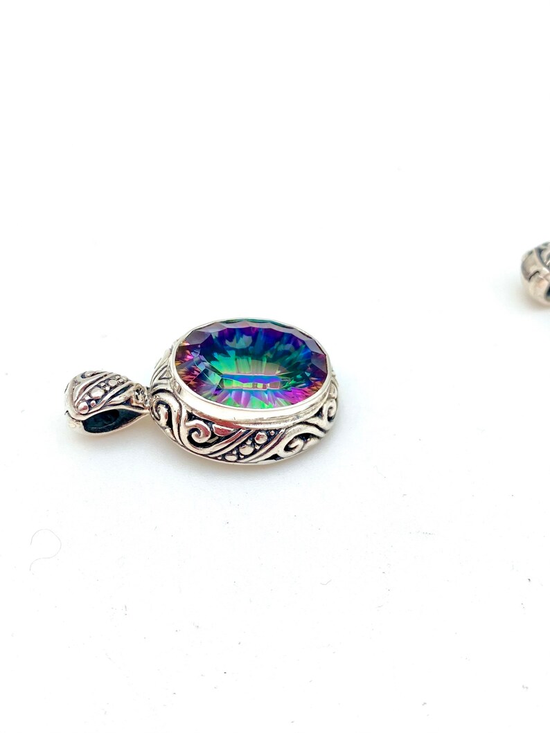 May include: A silver pendant with an iridescent gemstone set in a detailed filigree design.
