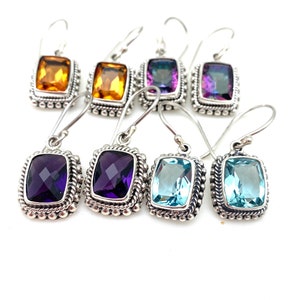 May include: Six pairs of silver earrings with different colored gemstones. The earrings feature a rectangular gemstone set in a silver bezel with a beaded border. The gemstones are orange, purple, and blue.