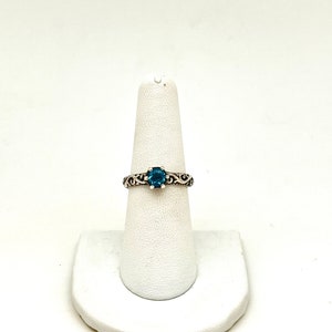 May include: A silver ring with a blue gemstone set in a delicate filigree design.