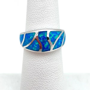 May include: A silver ring with a blue opal inlay. The opal is cut into a geometric pattern.