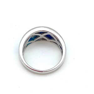 May include: A silver ring with a blue and white patterned design. The ring is viewed from the top, showing the inside of the band.