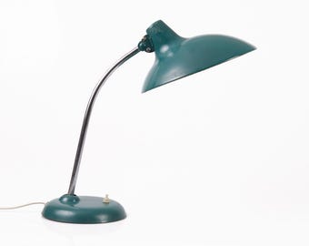 May include: A green metal desk lamp with a flexible arm and a round base. The lamp has a green metal shade.