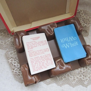 Könnte beinhalten: Eine Vintage-Spielbox mit einer blauen und weißen Karte, auf der "Whot" steht, und einer braunen Karte mit den Regeln für das Spiel "Waddingtons Whot".