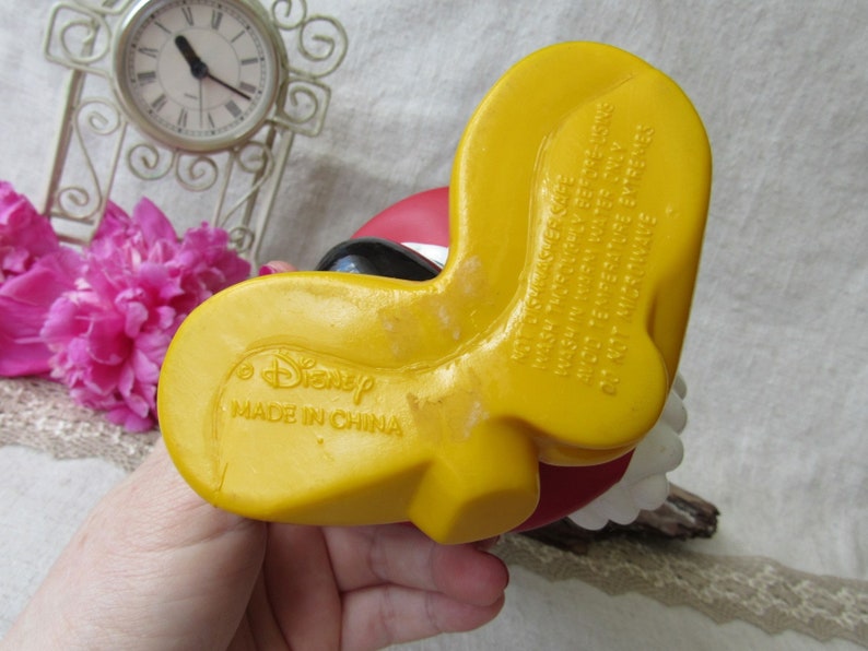 Puede incluir: Pie amarillo de una figura de Disney, con el texto "Disney MADE IN CHINA" visible. La figura tiene un dise&ntilde;o rojo y negro. La parte inferior del pie tiene el texto "NOT DISHWASHER SAFE WASH THOROUGHLY BEFORE USING WASH IN WARM WATER ONLY AVOID TEMPERATURE EXTREMES DO NOT MICROWAVE."