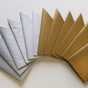 May include: A fan of silver and gold paper triangles. The triangles are arranged in a semi-circle with the silver triangles on the left and the gold triangles on the right.