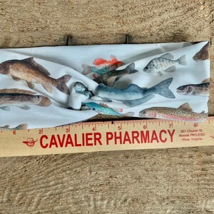 May include: White headband with a colorful print of various fish. The headband is made of a soft, stretchy fabric and is perfect for adding a touch of whimsy to any outfit.