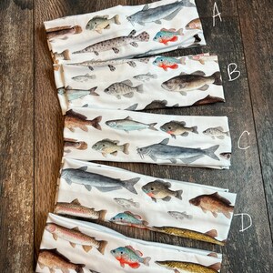May include: Five different headbands with a white background and colorful fish illustrations. The headbands are labeled A through E.