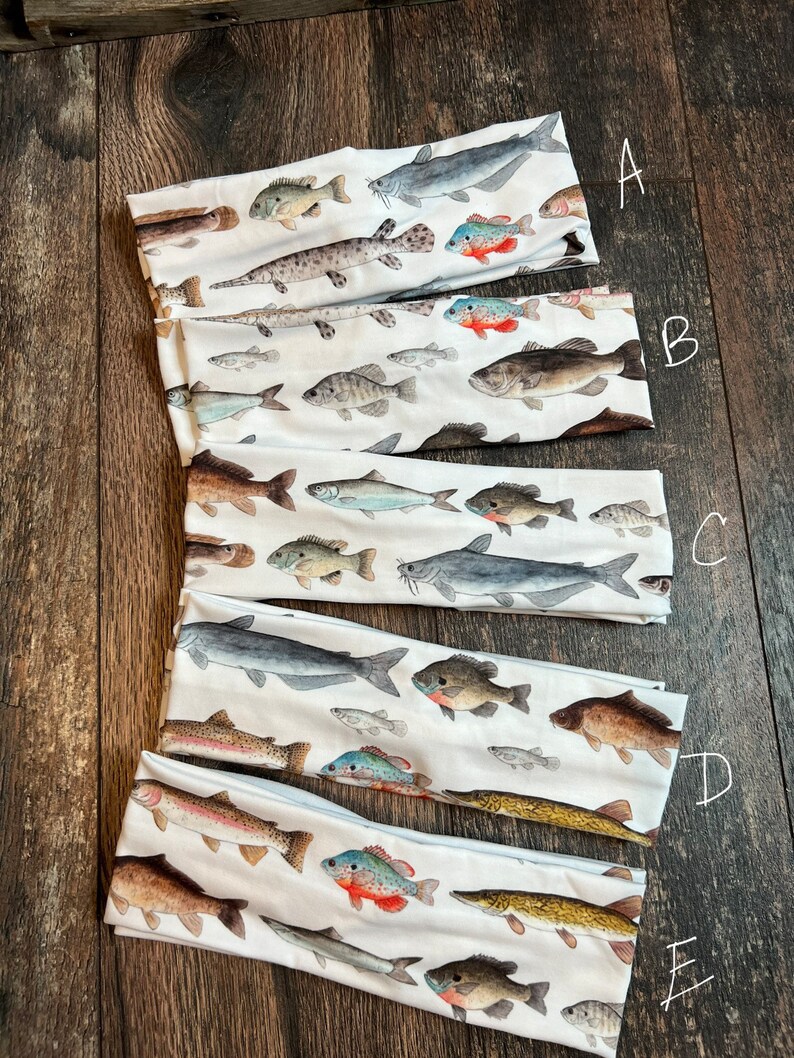 May include: Five different headbands with a white background and colorful fish illustrations. The headbands are labeled A through E.