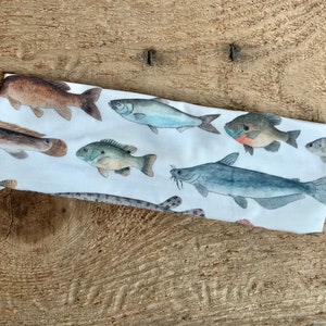 May include: White headband with a colorful fish print. The fish are various species, including catfish, bass, and sunfish.