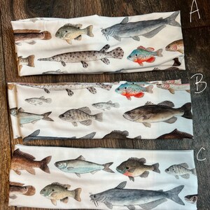 May include: Three white headbands with a variety of colorful fish printed on them. The headbands are labeled A, B, and C.