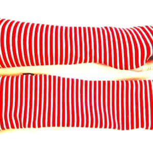 May include: A pair of red and white striped arm warmers. The arm warmers are made of a soft, stretchy fabric and are perfect for keeping your arms warm in the winter.