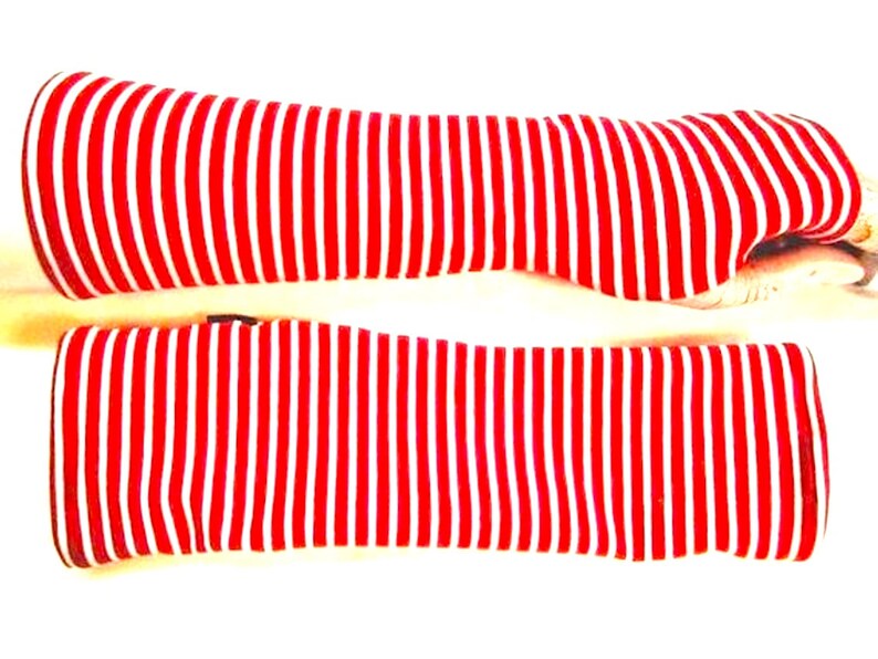 May include: A pair of red and white striped arm warmers. The arm warmers are made of a soft, stretchy fabric and are perfect for keeping your arms warm in the winter.