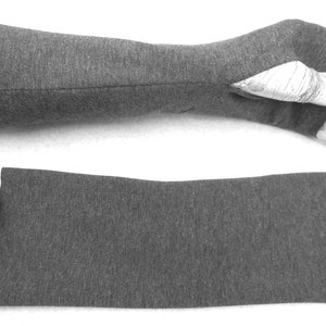 Op de afbeelding: Een paar grijze vingerloze armwarmers met een duimgat. De armwarmers zijn gemaakt van een zachte, rekbare stof en perfect om je handen warm te houden in de winter.