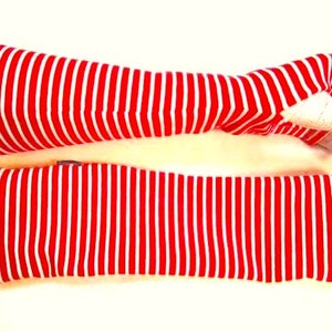 May include: A pair of red and white striped arm warmers. The arm warmers are made of a soft, stretchy fabric and are perfect for keeping your arms warm in the cooler months.