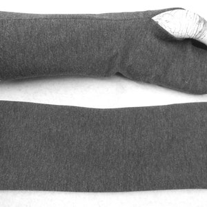 Op de afbeelding: Een paar grijze vingerloze armwarmers, een gevouwen en een uitgevouwen. De armwarmers zijn gemaakt van een zachte, rekbare stof.