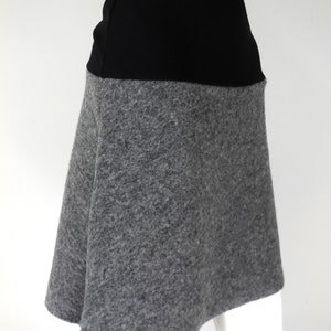 May include: A-line skirt with a black waistband and a grey, textured skirt. The skirt is made of a soft, wool-like material. The skirt is shown on a mannequin.