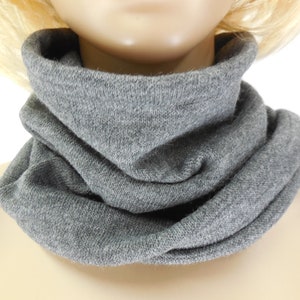 Könnte beinhalten: Grauer Strick-Halswärmer oder Schal. Der Halswärmer ist gefaltet und um den Hals getragen.