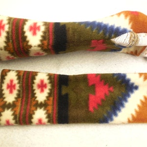 Op de afbeelding: Een paar vingerloze handschoenen met een kleurrijk geometrisch patroon in tinten bruin, rood, wit, blauw en groen. De handschoenen zijn gemaakt van een zachte, pluche stof.