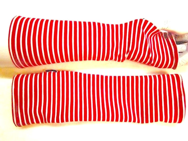 May include: A pair of red and white striped arm warmers. The arm warmers are made of a soft, stretchy fabric and are perfect for keeping your arms warm in the cold weather.