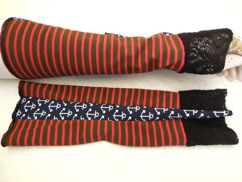 May include: A pair of brown and red striped arm warmers with black lace trim. One warmer has a navy blue band with white anchor print.