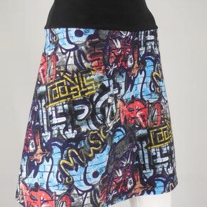 Könnte beinhalten: Ein schwarzer und blauer Rock mit Graffiti-Druck. Der Rock hat einen schwarzen Bund und eine ausgestellte Silhouette.