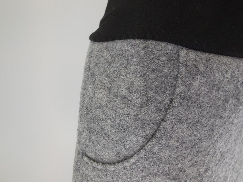 K&ouml;nnte beinhalten: Nahaufnahme einer grauen Jogginghose mit einer gro&szlig;en Tasche auf der linken Seite.