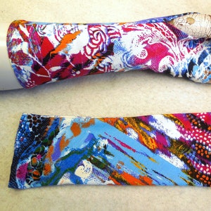 Pode incluir: Dois pares de aquecedores de braço de tecido coloridos. O primeiro par tem um padrão floral em tons de rosa, branco, laranja e azul. O segundo par tem um padrão mais abstrato com cores azul, laranja, branco e rosa.