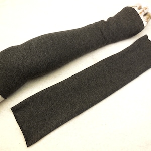 May include: A pair of gray arm warmers made of a soft, stretchy fabric. The arm warmers are laid flat on a white surface.