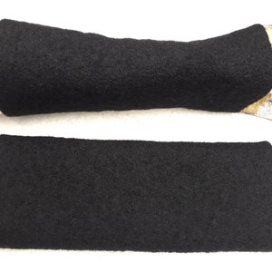 Pode incluir: Dois aquecedores de braço de lã preta. Os aquecedores de braço são feitos de um material macio e felpudo.